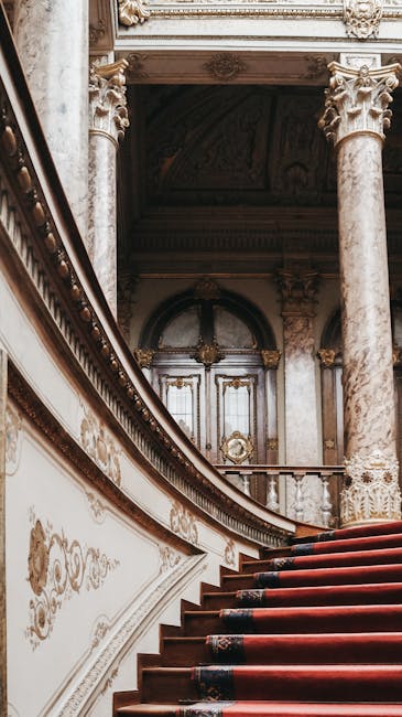 A close-up view of a modern vacuum cleaner with a transparent dust collection chamber filled with debris, positioned on a beige carpeted floor against a plain white wall. The vacuum features a flexibl