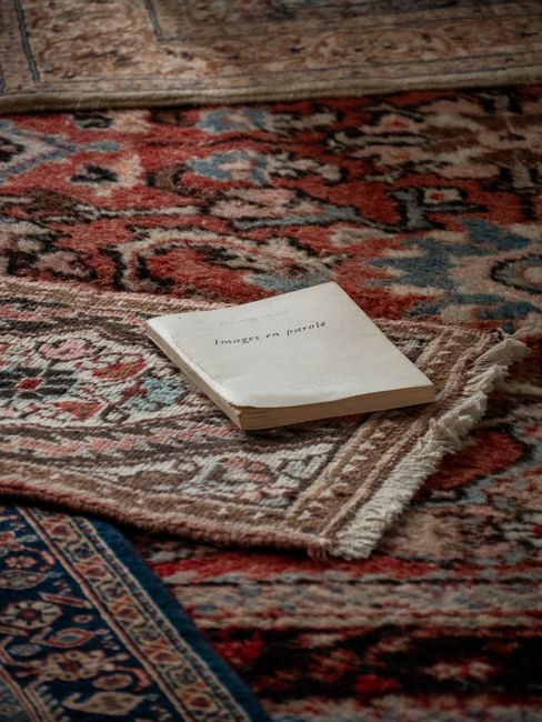 Close-up of a beige carpet with a textured pile, showing a noticeable difference between a visibly dirty, stained section and a freshly cleaned, bright section, demonstrating surface cleaning and deep